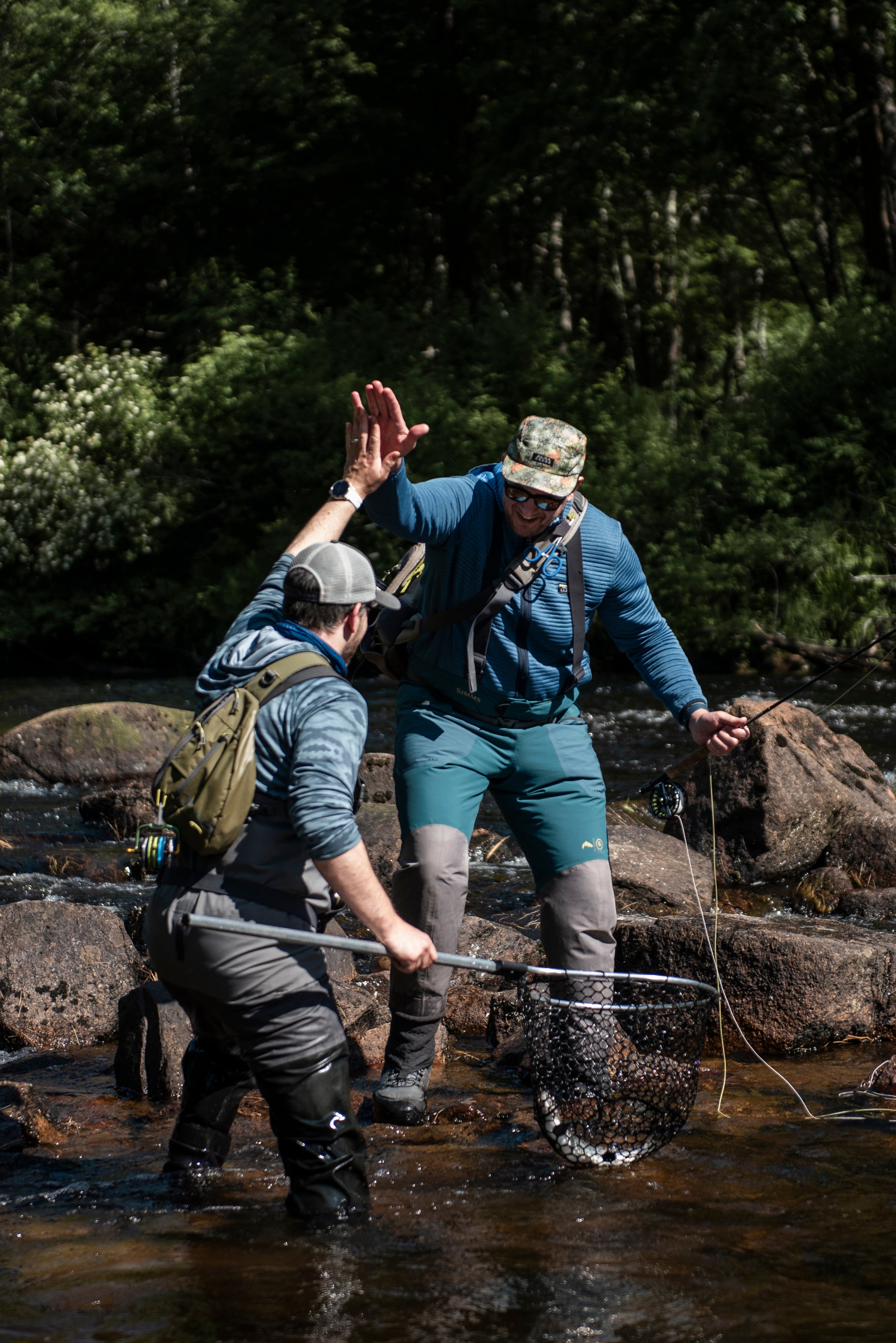 Two fishermen celebrating the catch of a landlocked salmon with a high five