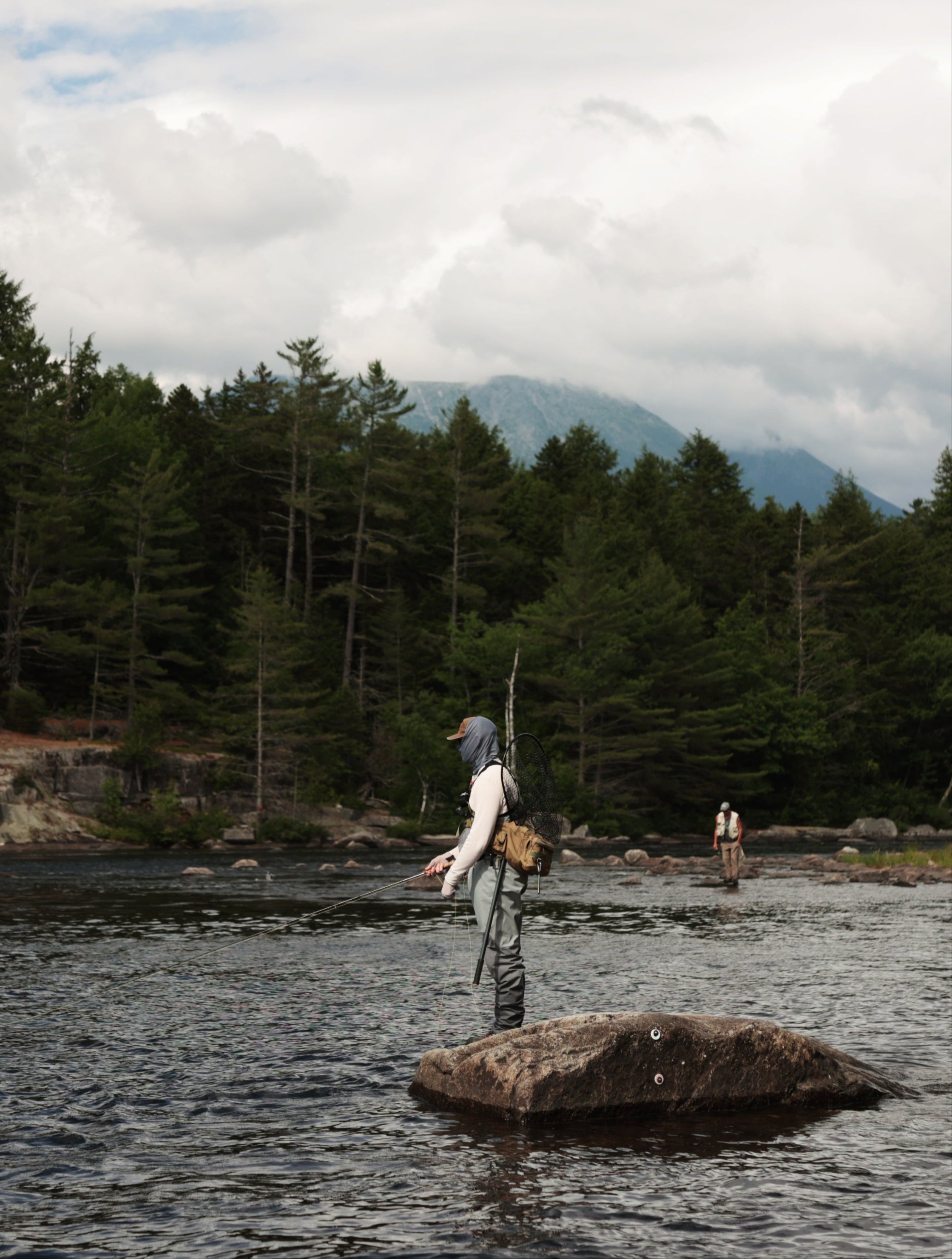 angler fly fishing the west branch penobscot river with mount katahdin in the background